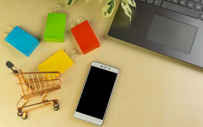 Ecommerce cart with bags phone and laptop in flat lay composition