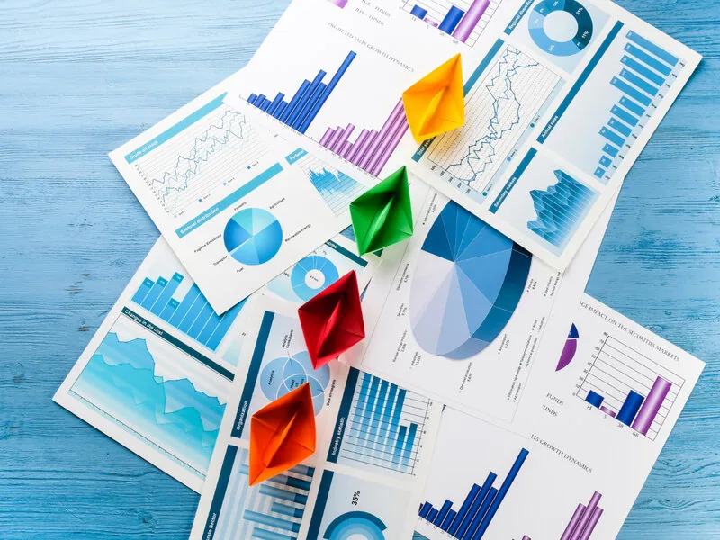 Paper boats on colorful business charts illustrating vanity growth
