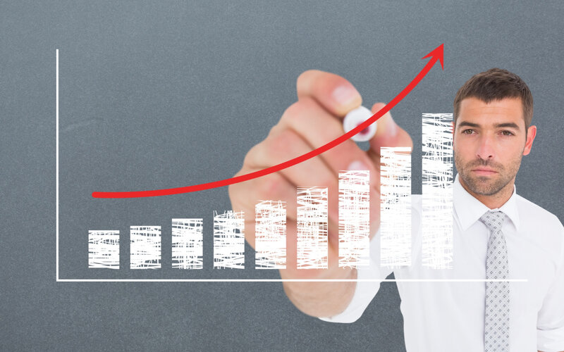 Businessman drawing a rising growth chart with arrow on paper